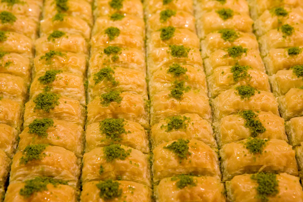 Rows of golden baklava, each topped with green pistachios